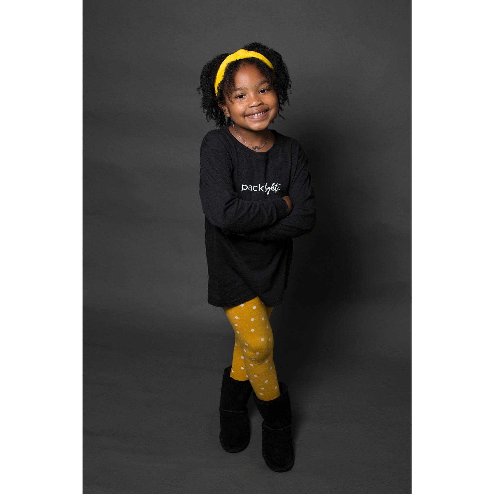 smiling girl model wearing black long sleeve affirmation tee that says Pack Light by Sol Rise Essentials 