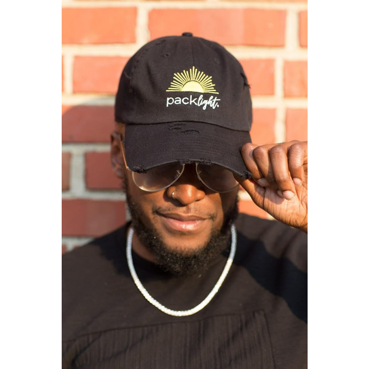 male model wearing Pack Light affirmation cap with sun graphic from Sol Rise Essentials 