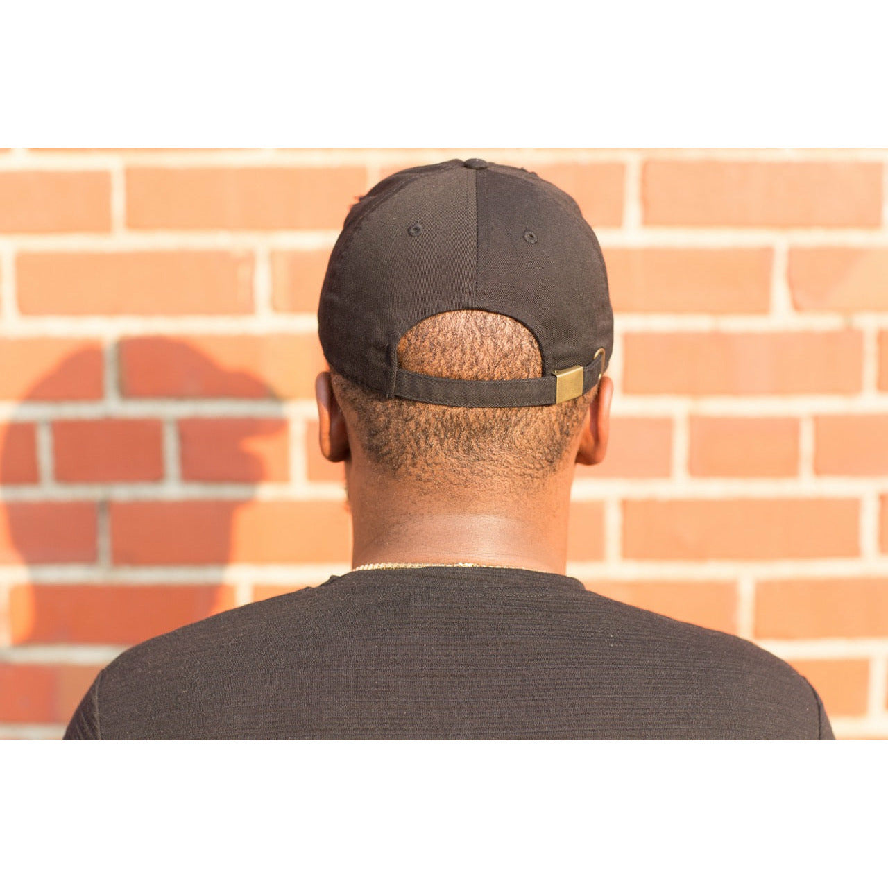 man showing back of Pack Light affirmation Dad cap hat with tucked strap from Sol Rise Essentials