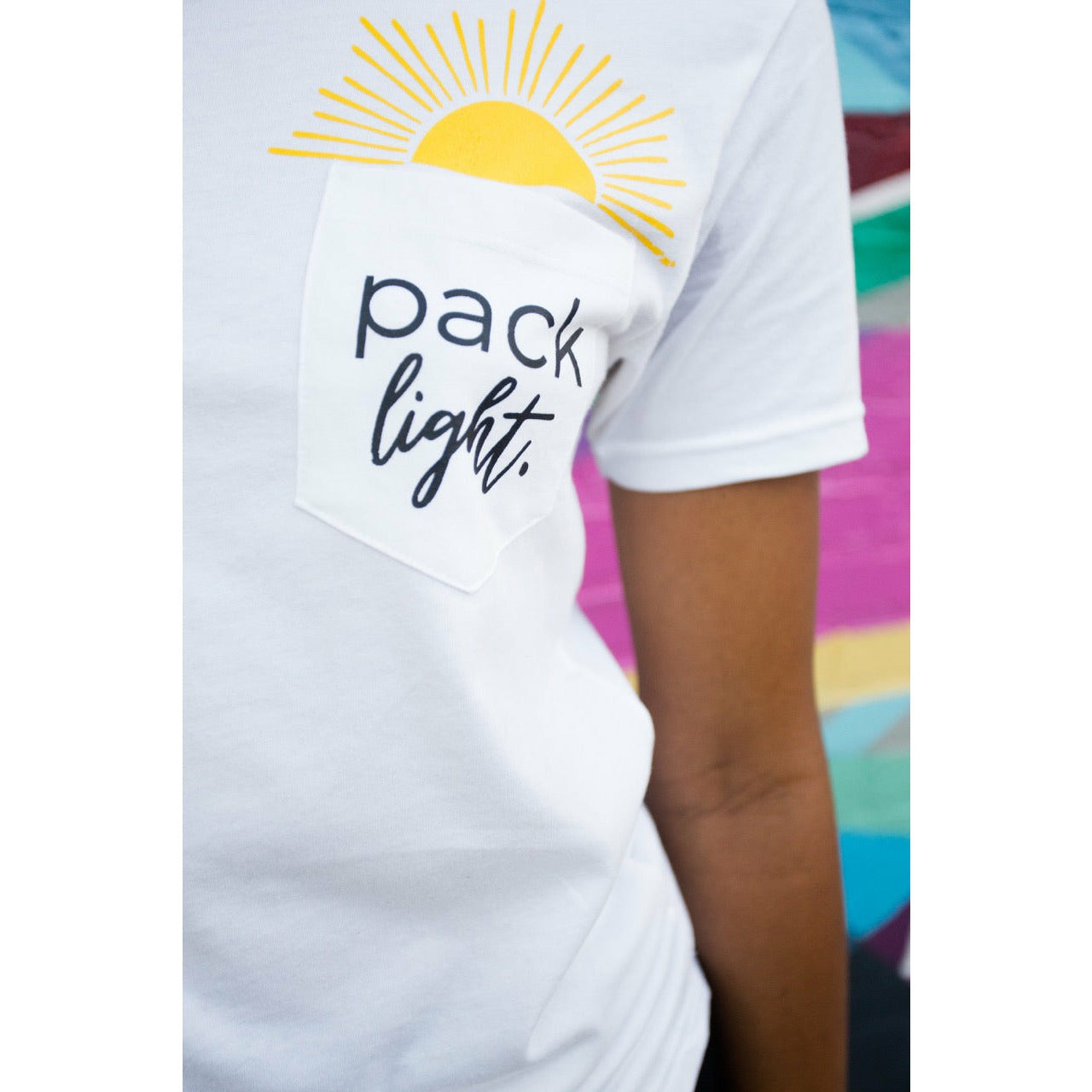 close up of Pack Light affirmation t-shirt with pocket and sun