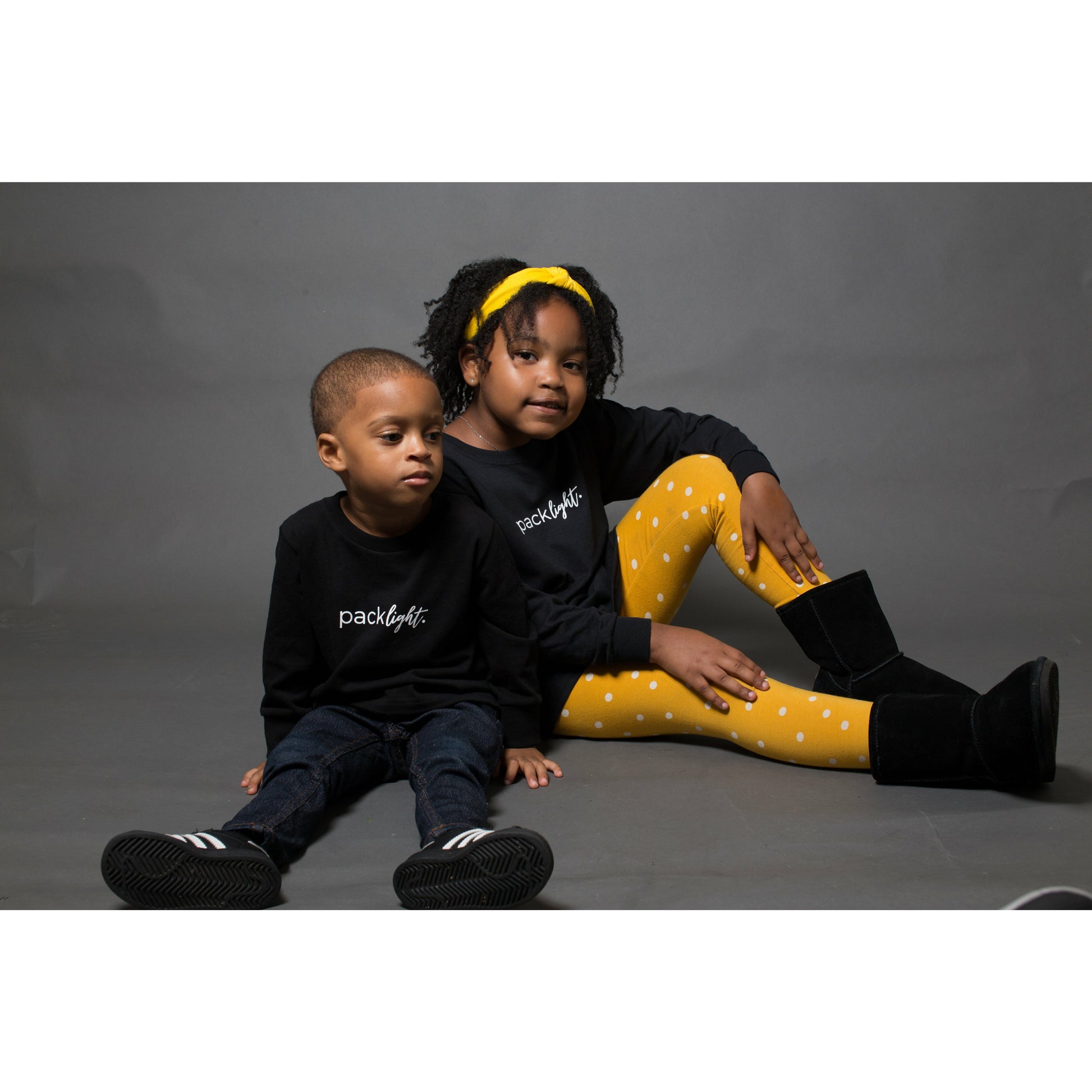 boy and girl models wearing black long sleeve affirmation tee that says Pack Light by Sol Rise Essentials 