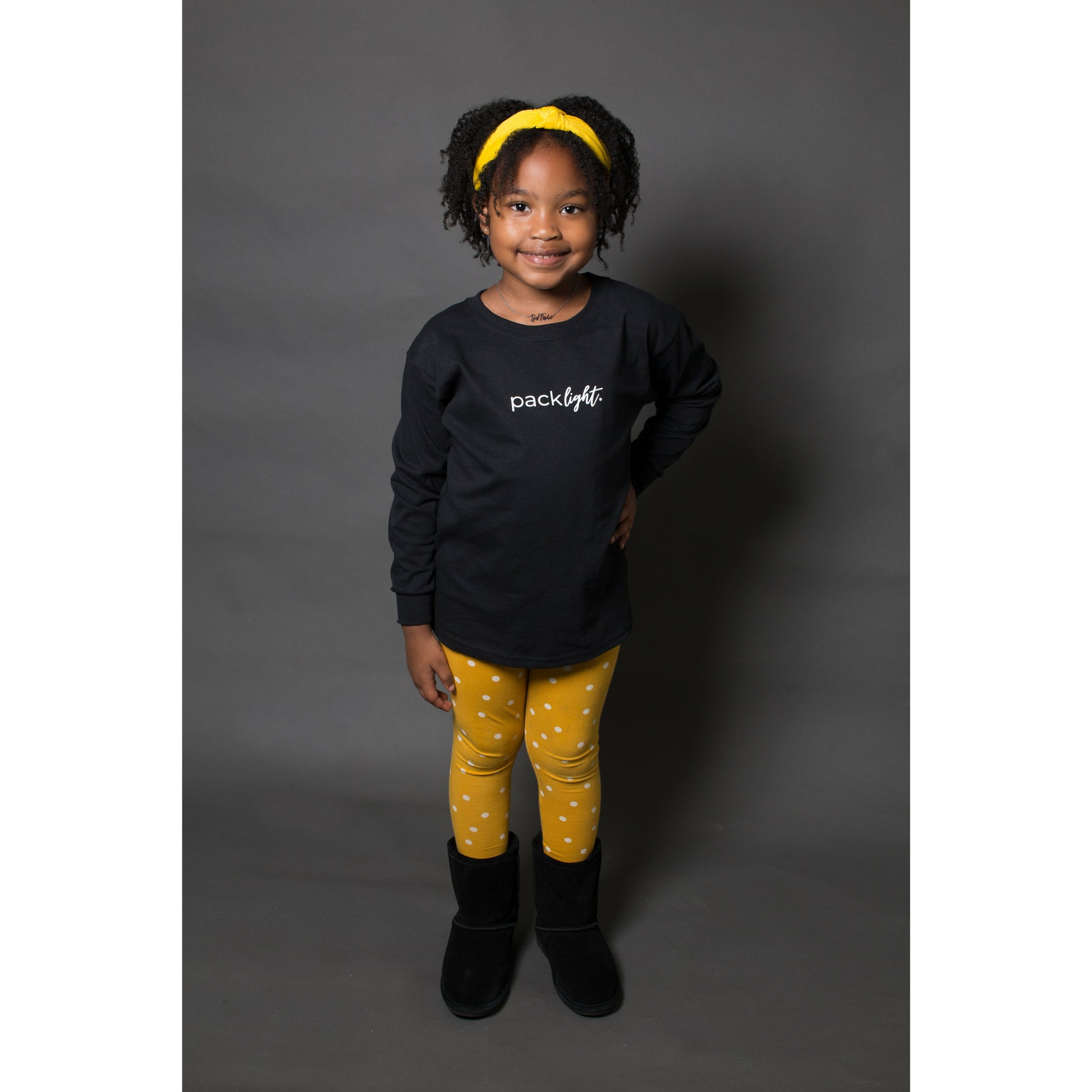 girl model wearing black long sleeve affirmation tee that says Pack Light by Sol Rise Essentials 