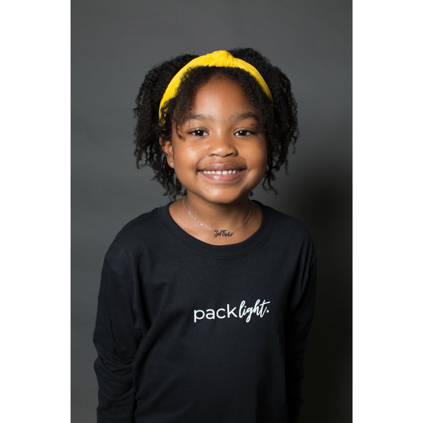 girl model wearing black long sleeve affirmation tee that says Pack Light by Sol Rise Essentials 
