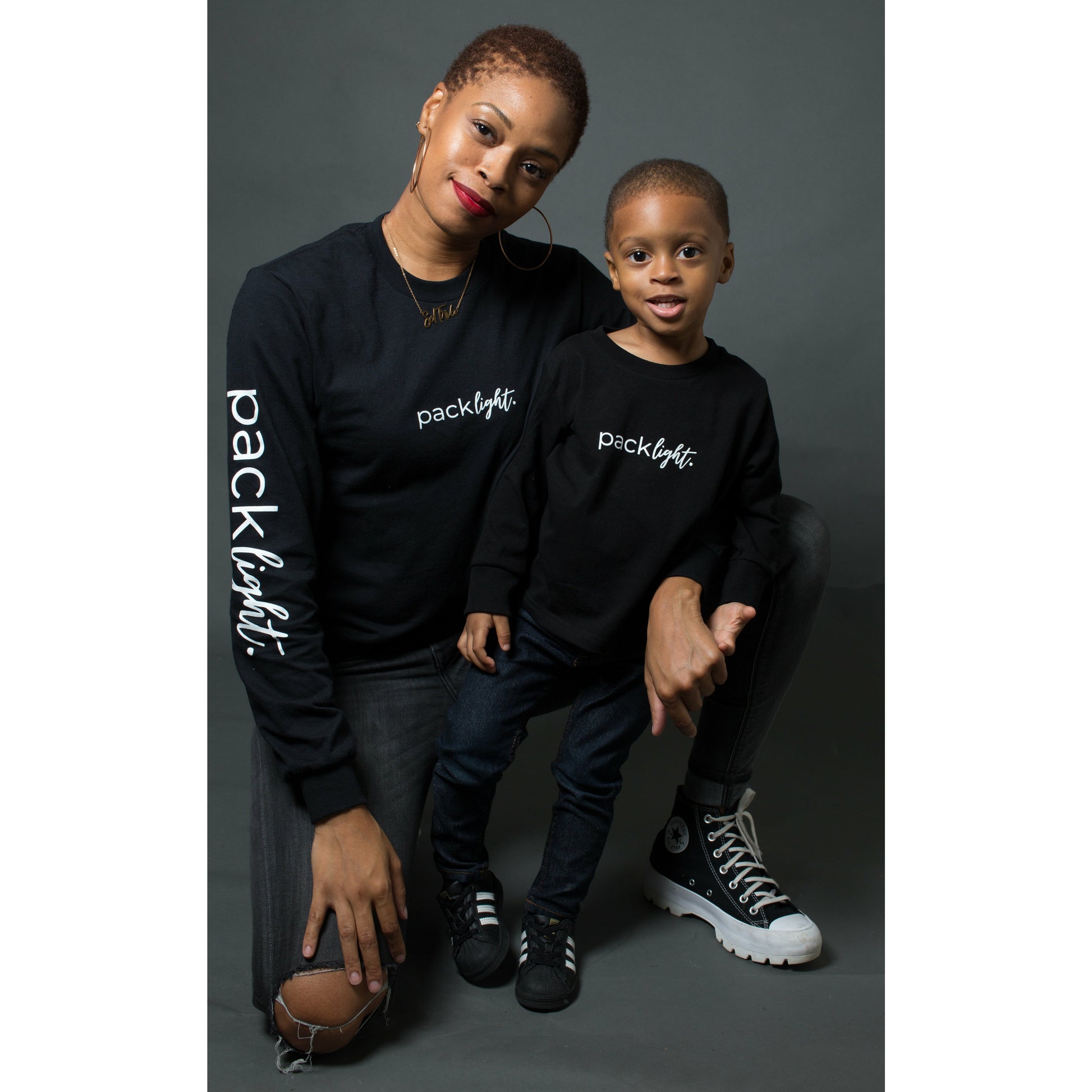 woman and boy models wearing black long sleeve affirmation tee that says Pack Light by Sol Rise Essentials 