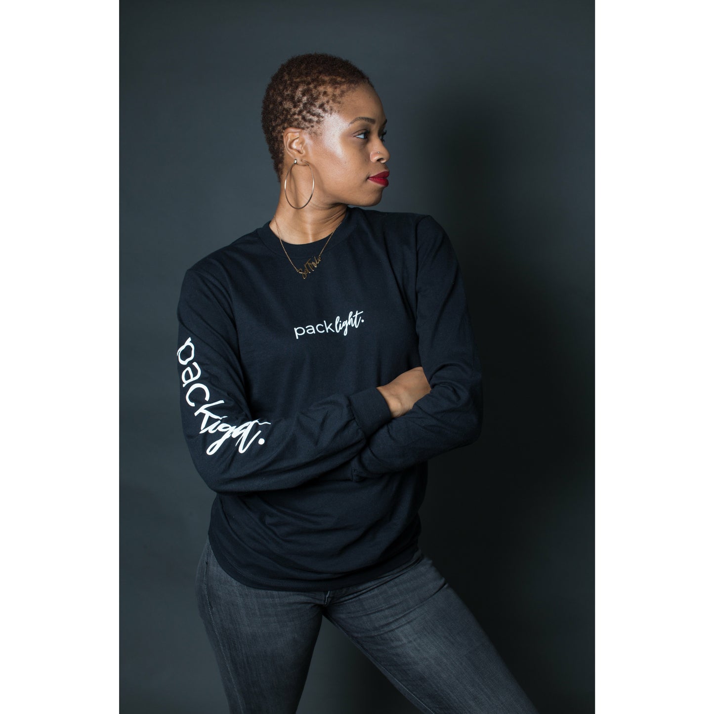 woman model wearing black affirmation tee that says Pack Light on the sleeve and front of the tee by Sol Rise Essentials