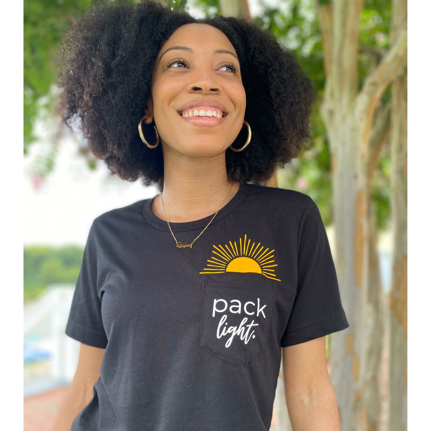 smiling model in black Pack Light affirmation tee from Sol Rise Essentials